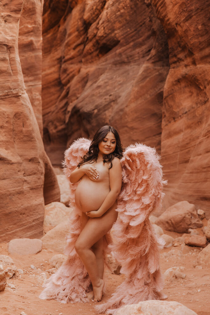 Mother posing in Angel wings for maternity session at slot canyon