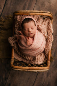 baby girl in pink wrap in rattan bed for phoenix newborn session