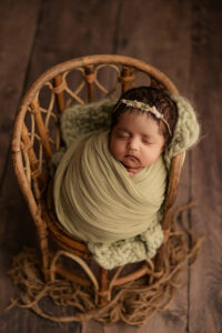 Baby wrapped in sage green wrap for newborn portraits