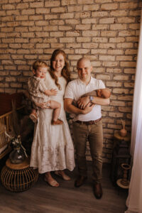 Family of 4 posing in front of brick wall for portraits