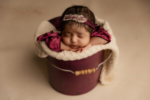 Baby posed in purple bucket for phoenix newborn session