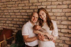 Mom and dad posing with newborn baby for newborn portrait sessions