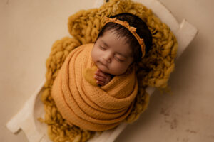 Baby wrapped in yellow fabric for newborn portraits in phoenix