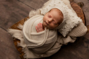Newborn baby bundled in white wrap for newborn studio portraits