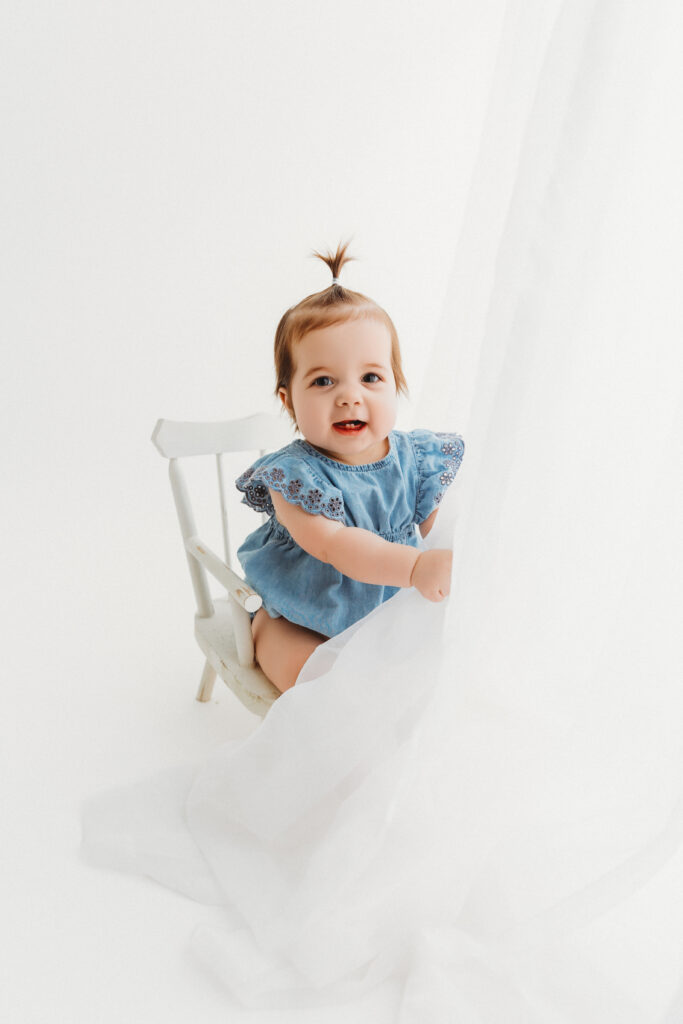 Baby during portrait session in Phoenix in blue outfit and white chair