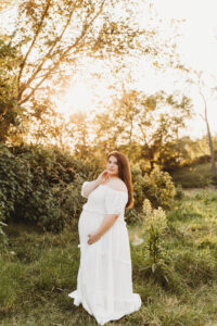 Mom posing in white boho dress in maternity session