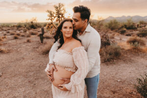 Pregnant mother posing at lost dutchman for maternity portrait session at sunset with husband