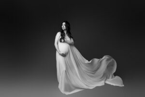 black and white maternity portrait of woman in white fabric