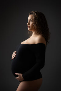 Side profile of maternity portrait session with mom wearing black body suit