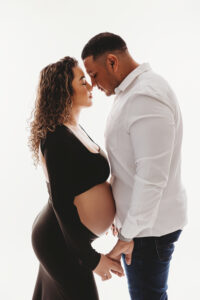 maternity photographer studio in phoenix mom posing in black sleek maternity gown with dad