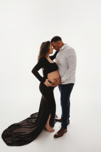 Hispanic maternity photography photography session mom wearing black dress posing with dad