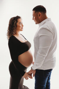 Pregnancy photographer studio in phoenix mom posing in black sleek maternity gown 