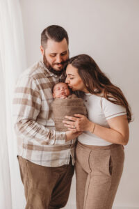 Mom, dad, and baby posing for newborn session at phoenix photography studio. Learn on how to save money on your newborn session 