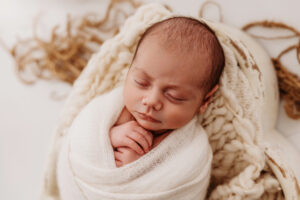 Close up of Baby wrapped in cream wrap for simple newborn session at phoenix newborn photography studio