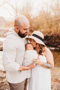 Baby, mom, and dad posing for sunset family session