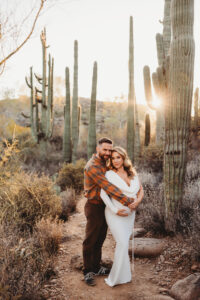 Mom and dad posing for sunset maternity session with cacti in desert