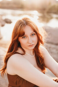 Girl in red dress posing on rock at salt river in Phoenix Arizona for senior session 