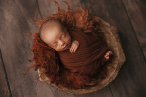 African American baby wrapped in a rust wrap for a newborn session in scottsdale Arizona newborn photography studio