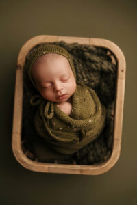 Black baby wrapped in a green blanket with hat