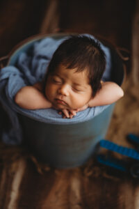 Baby boy posing in bucket for newborn session in Phoenix Arizona at the best newborn photography studio