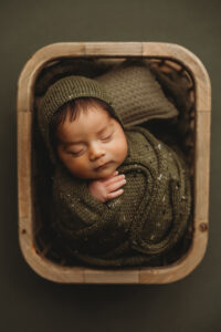 Baby boy posing in bucket for newborn session in Phoenix Arizona at the best newborn photography studio