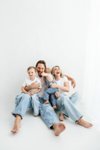 Family of 4 playing on phoenix photography studio floor in jeans and white shirt 