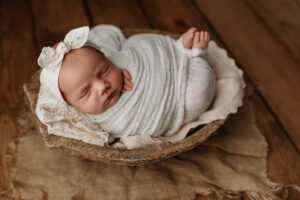 newborn baby girl posed in wooden bowl during phoenix newborn photoshoot